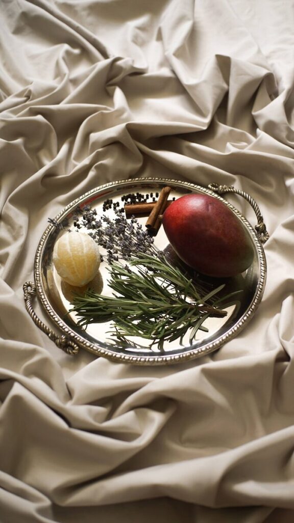 Photo by Cosmin Ursea a silver plate topped with fruit on top of a bed