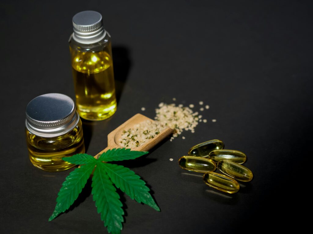 High-quality image featuring cannabis oil, seeds, leaves, and capsules on a dark background.